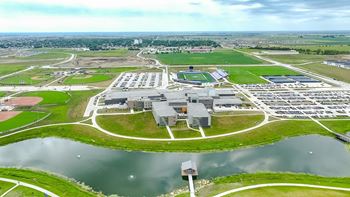 an aerial view of an industrial park with a body of water at Rialto Townhomes Apartments, Waukee, 50263